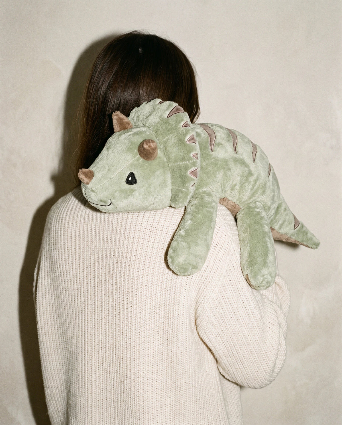 Woman seen from behind with the weighted Dinosaur in Matcha over her shoulder #Colour_Matcha