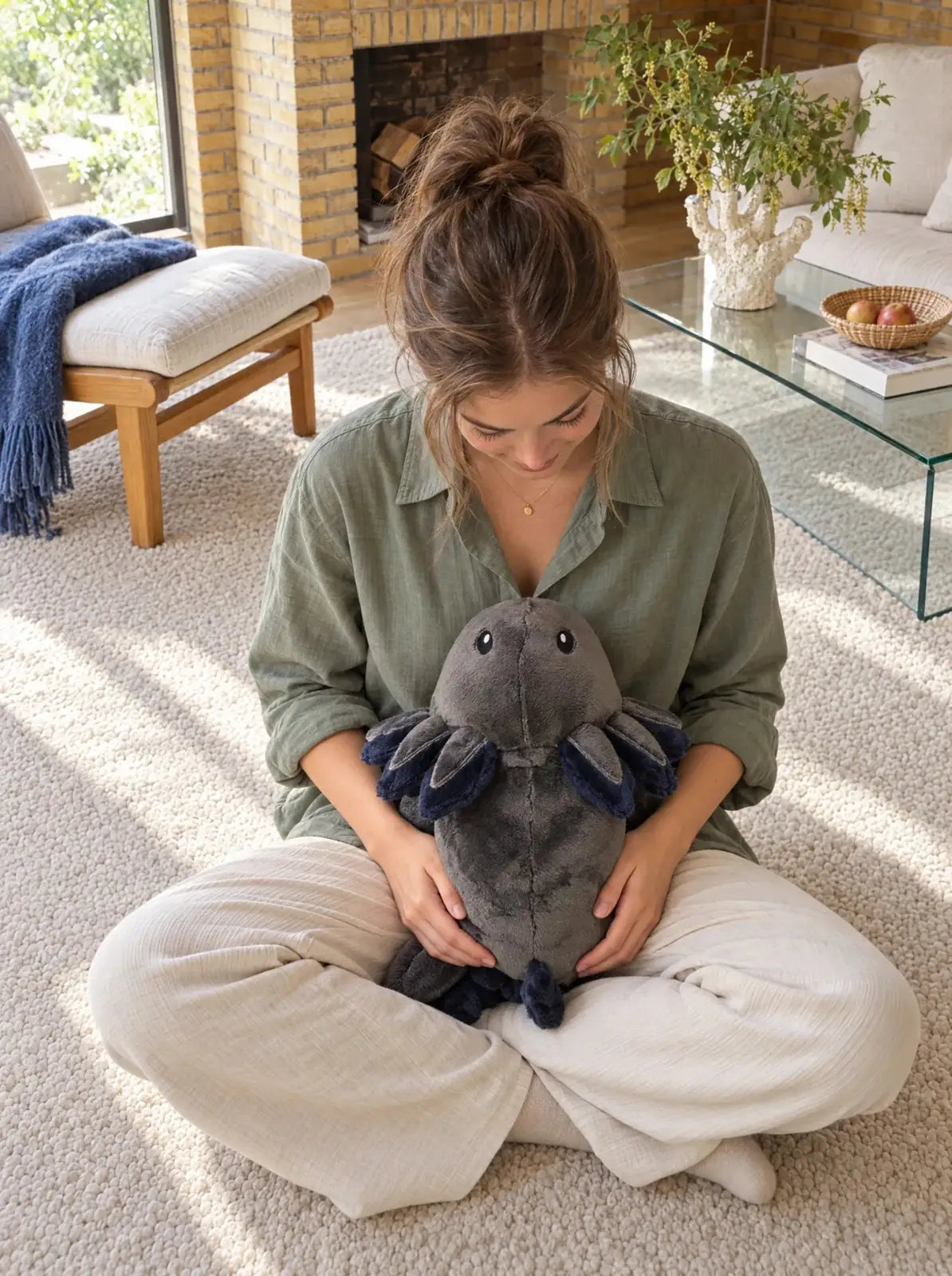 Woman sitting on the floor with the weighted Axolotl in Blue Flame in her lap