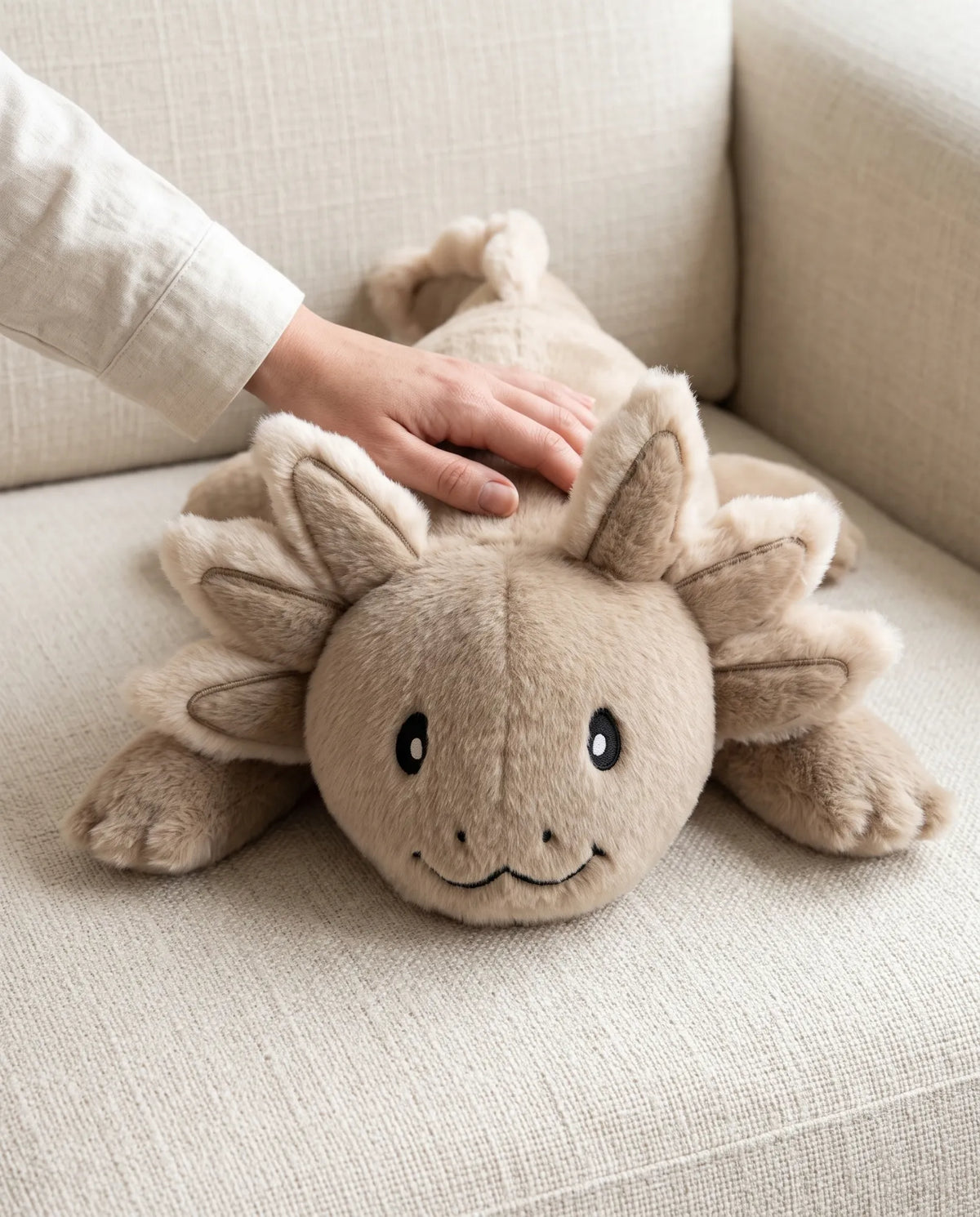 Hand resting on the weighted Axolotl in Mushroom on a sofa #Colour_Mushroom