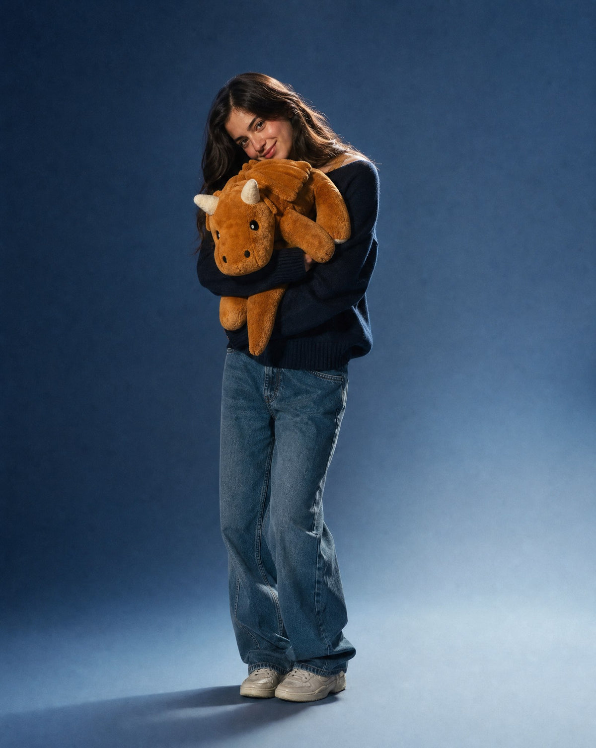 Woman in a navy jumper holding the 2.3 kg Brease Weighted Dragon plush, full length shown for scale