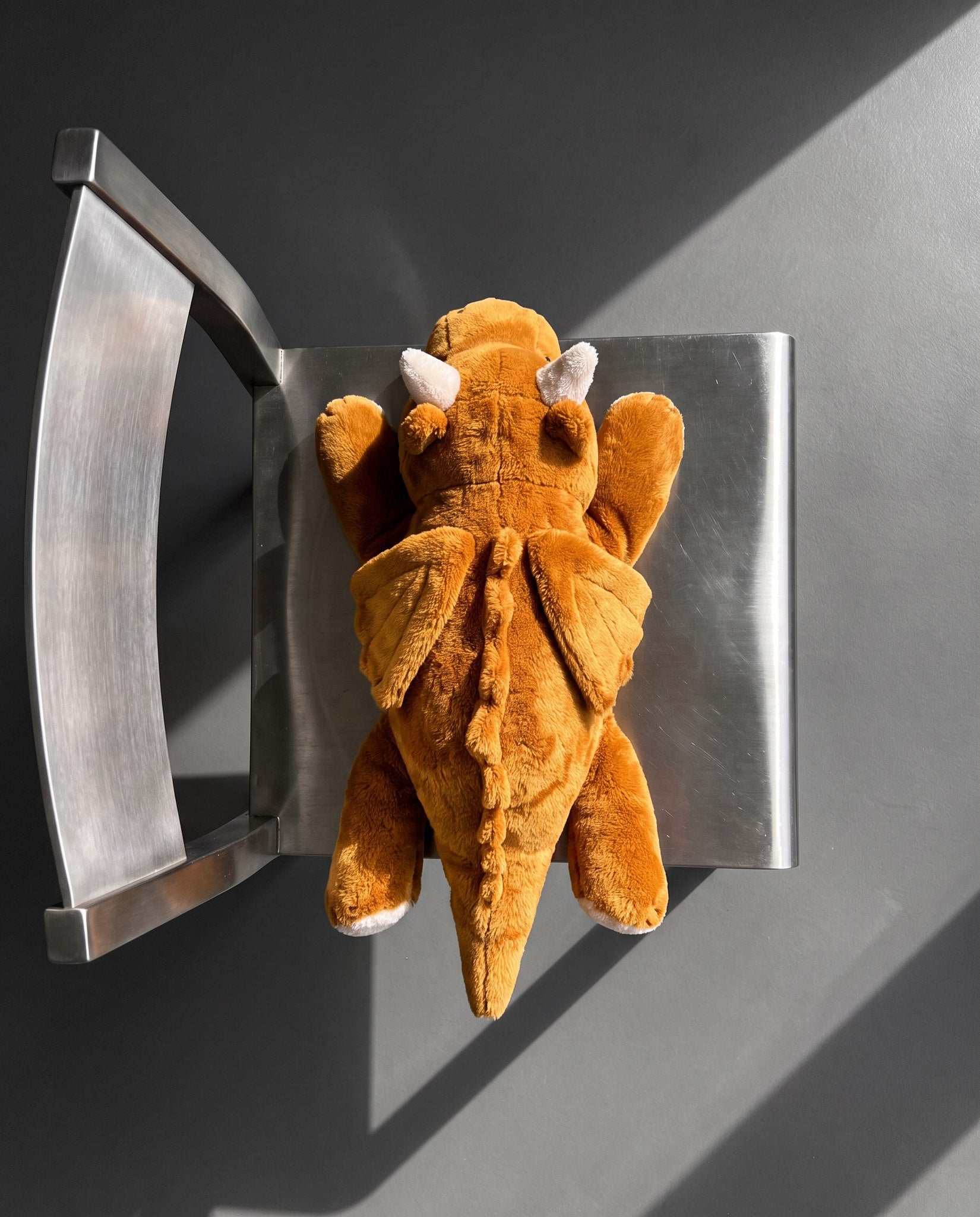 Brease Weighted Dragon 5 lb seen from above on a steel chair, showing the ochre wings and spine spikes