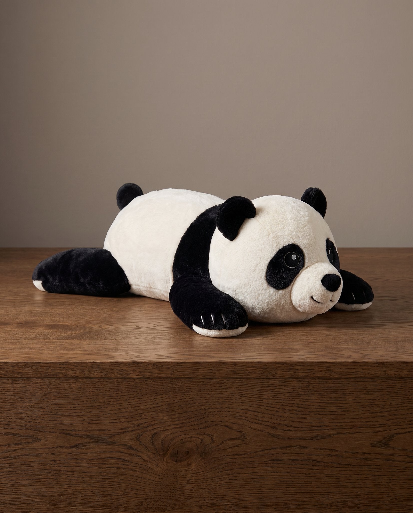 Brease weighted panda 45 cm lying on an oak ledge, studio
