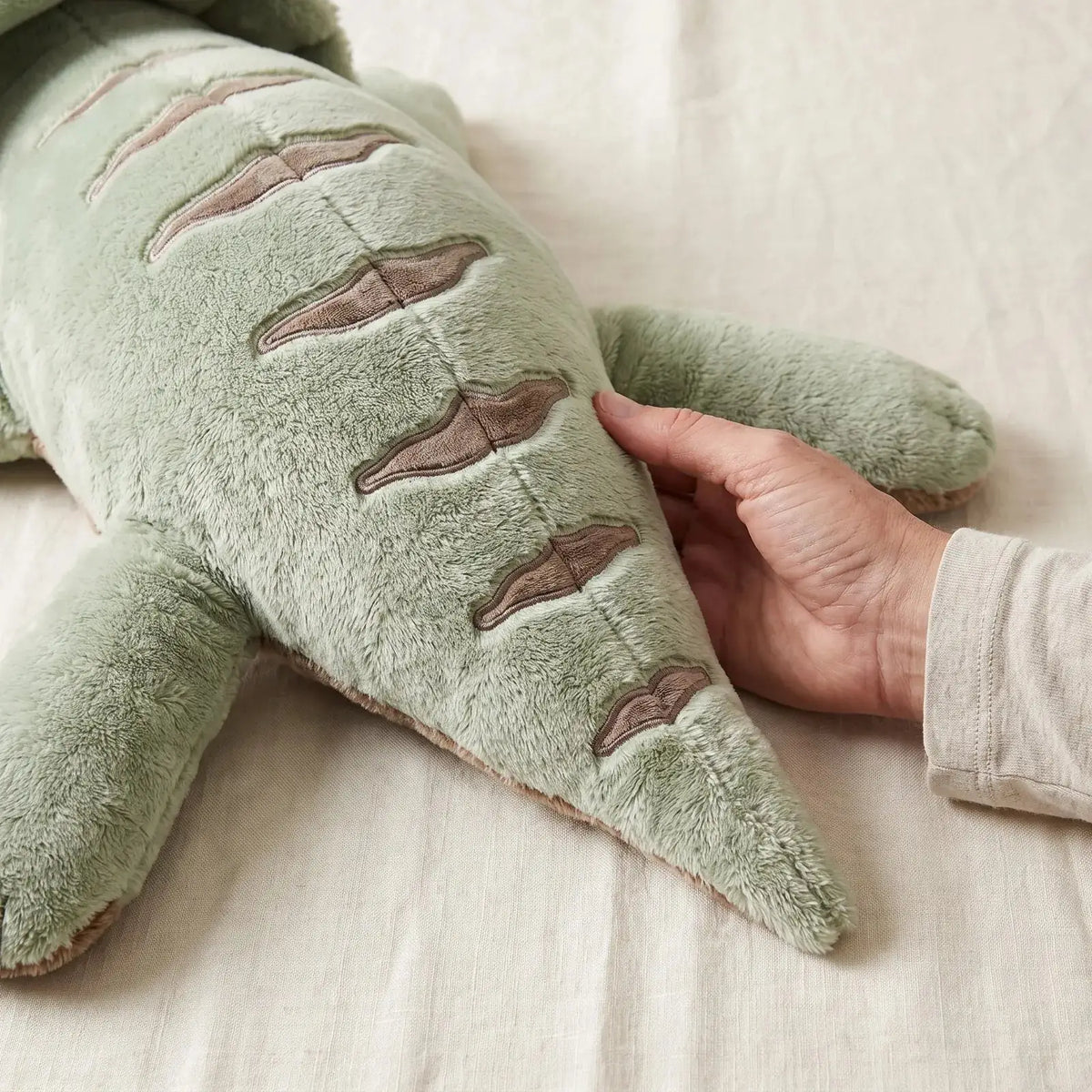 Hand resting on the soft fur of the weighted Dinosaur in Matcha