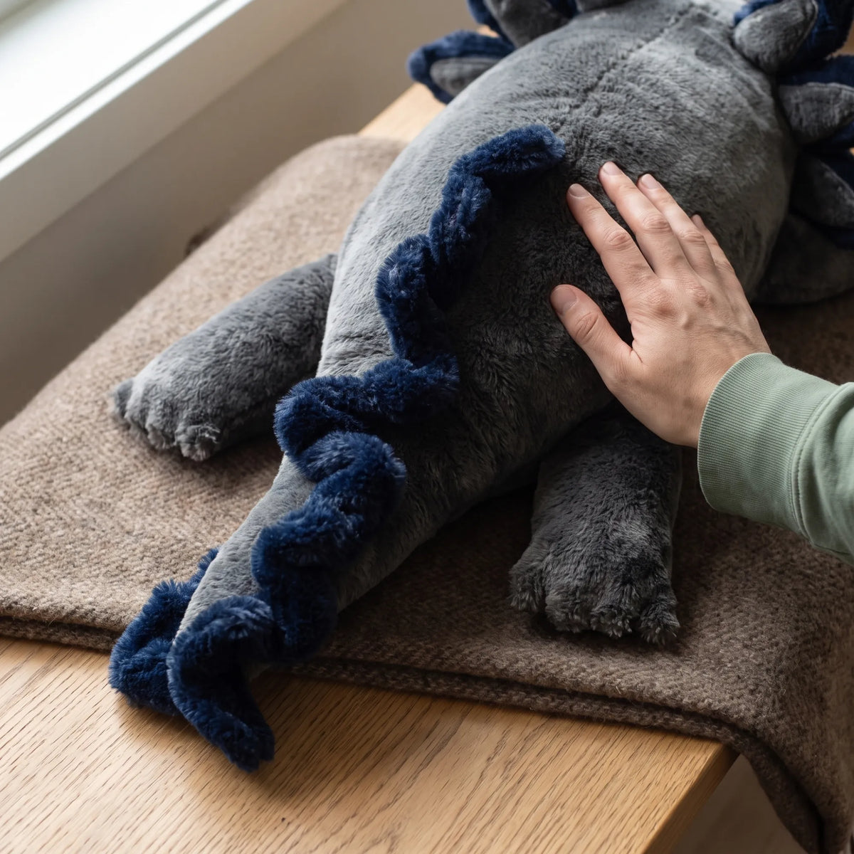 Hand resting on the soft fur of the weighted Axolotl in Blue Flame