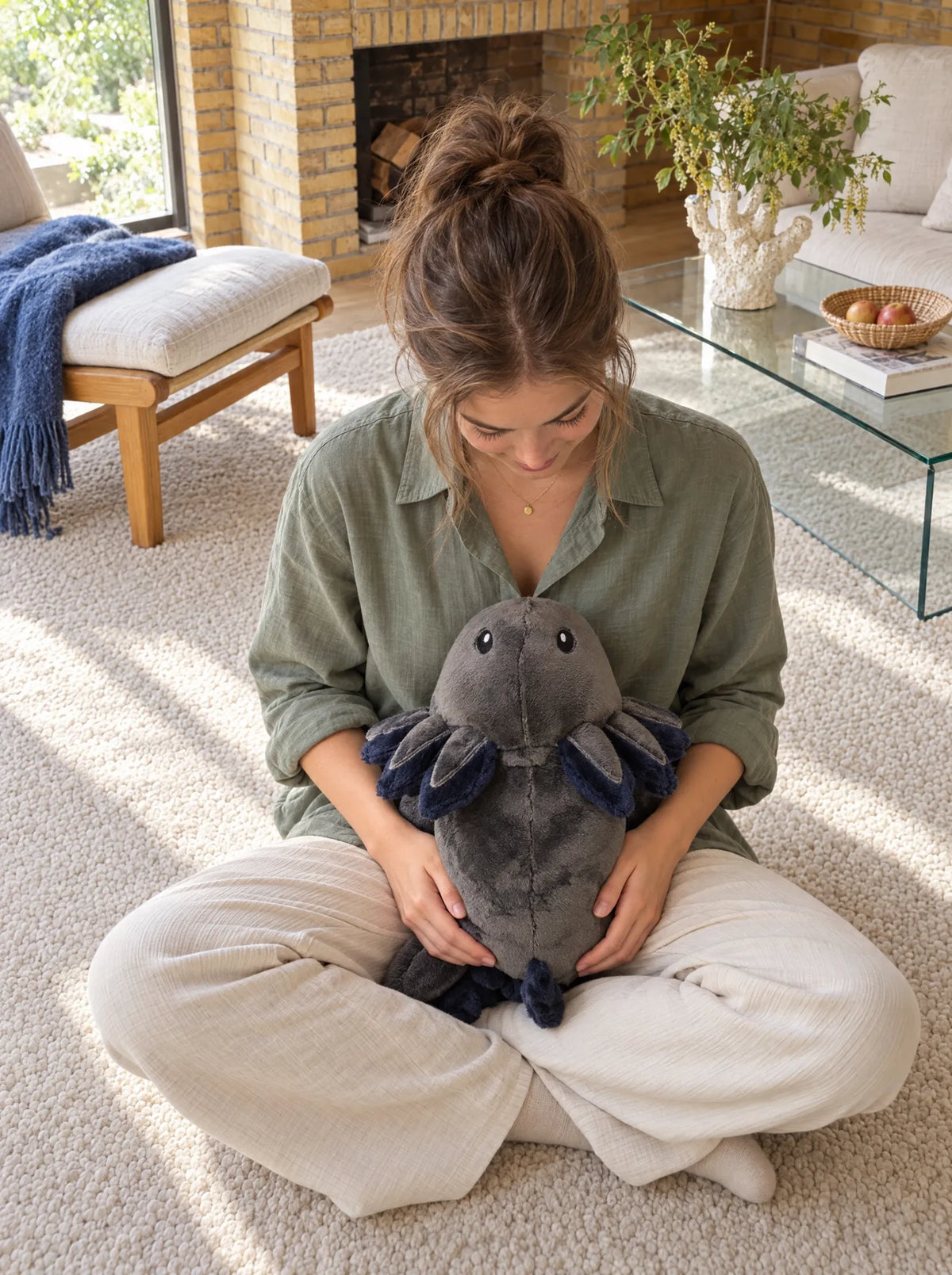 Woman sitting on the floor with the weighted Axolotl in Blue Flame in her lap