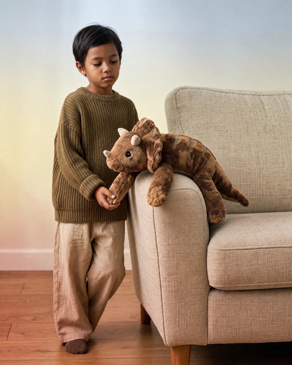 Child holding the paw of the weighted Dinosaur in Coffee on the sofa arm #Colour_Coffee