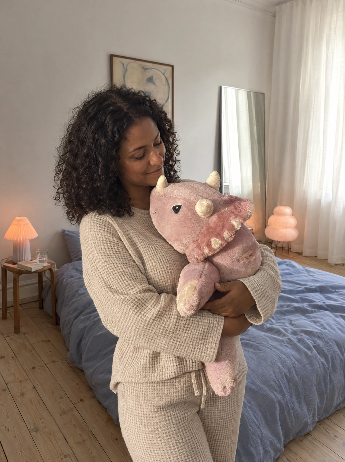 Woman in the bedroom hugging the weighted Dinosaur in Wild Rose #Colour_Wild Rose