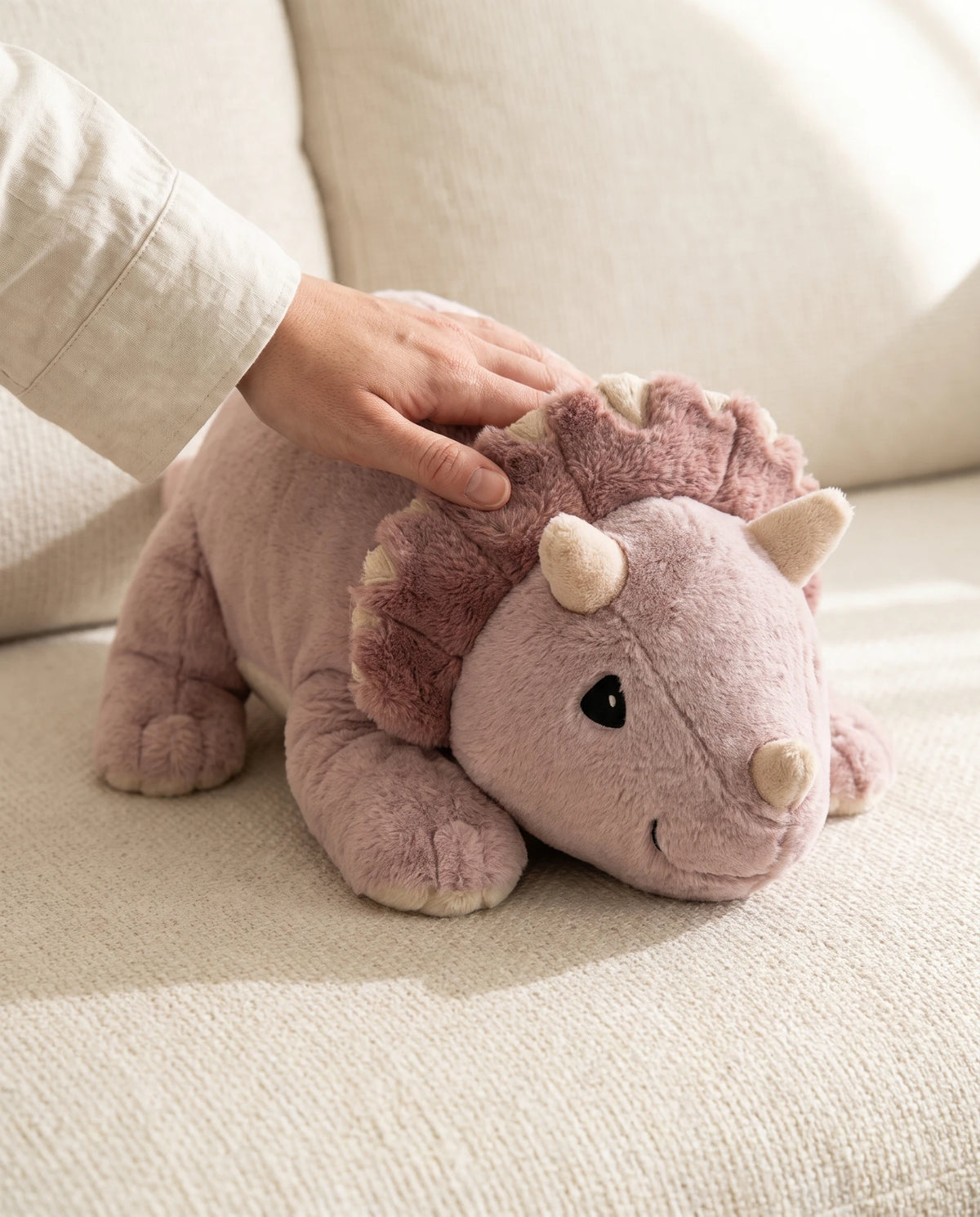 Hand stroking the weighted Dinosaur in Wild Rose on the sofa #Colour_Wild Rose
