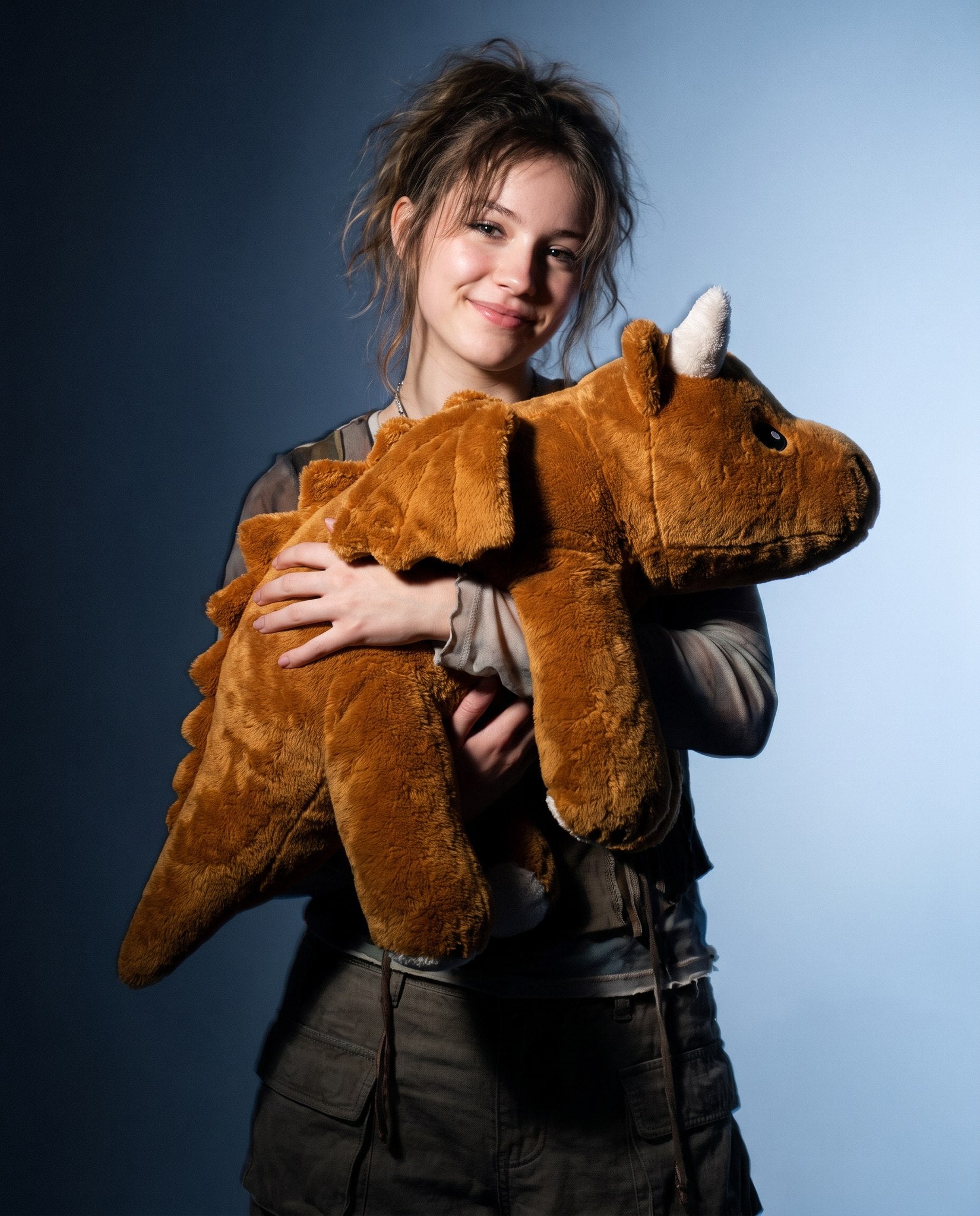Teenage girl carrying the Brease Weighted Dragon 5 lb in both arms, showing its weight and softness