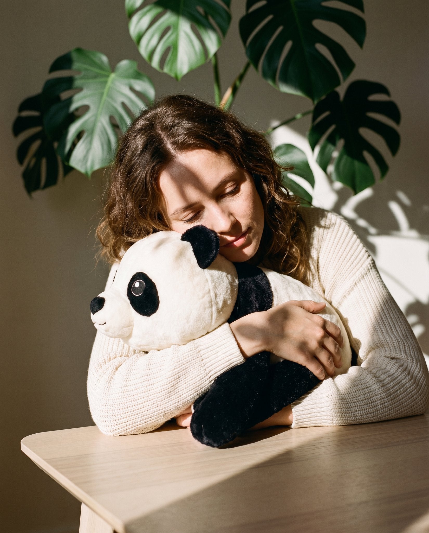 Woman resting her head on the Brease weighted panda in sunlight