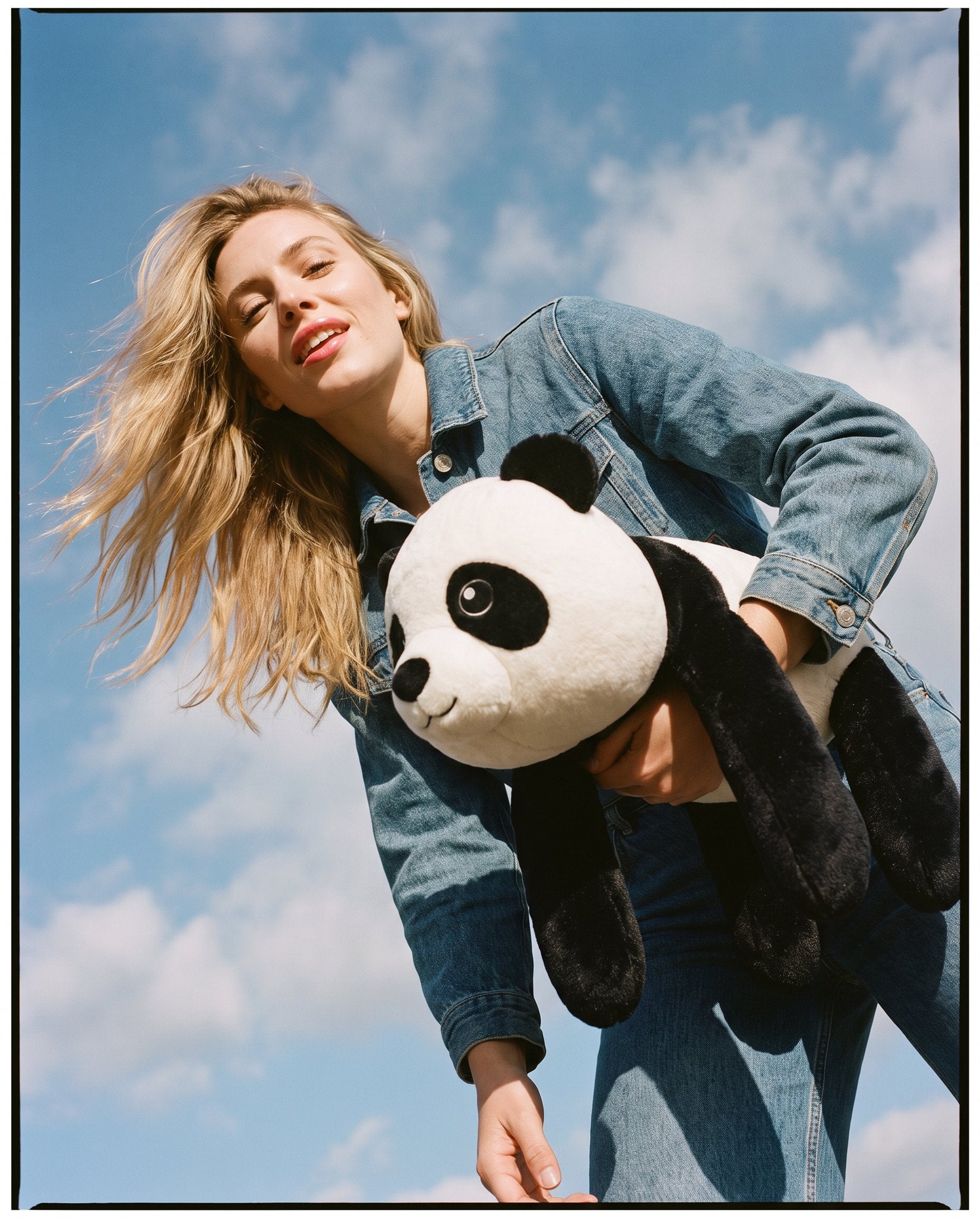 Woman in denim carrying the Brease weighted panda outdoors against a blue sky